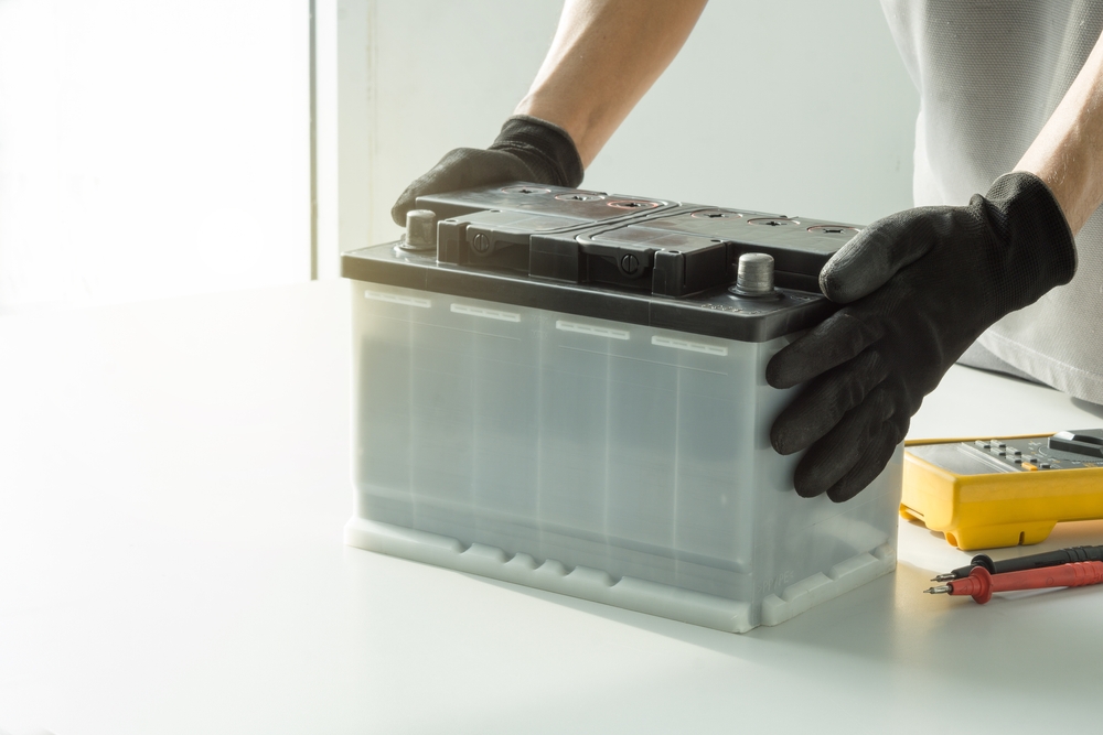 Auto,Mechanic,Checking,Car,Battery,On,Blurred,Multimeter,On,Background.